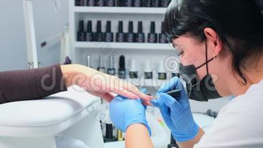 医生正在美容院给顾客的指甲美容院给客户的指甲涂上凝胶抛光剂。 竖起钉子。 假人